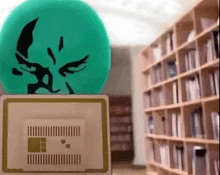 a green ball with a face on it is sitting on top of a box in a library