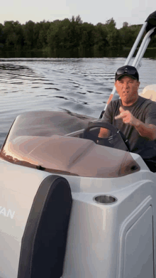 a man is driving a boat in the water and making a funny face