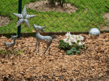 a garden with a fence and a few statues of deer