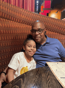 a man and a girl are sitting at a table with a menu in front of them