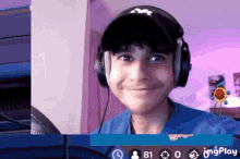 a boy wearing headphones and a hat is smiling while looking at the camera .