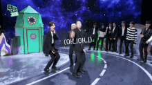 a group of men are dancing in front of a green rocket and a sign that says ohliohld