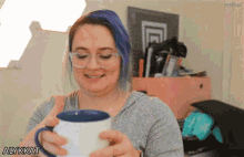 a woman with blue hair and glasses is holding a cup of coffee with the word alykkat on the bottom