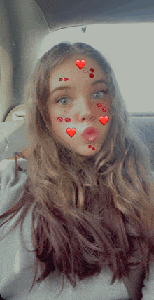 a girl with hearts on her face is sitting in the back seat of a car