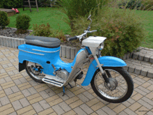 a blue and white motorcycle is parked on a brick sidewalk