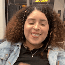 a woman with curly hair is smiling with her eyes closed in front of a sign that says more time