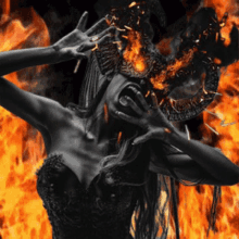 a woman with horns is screaming in front of a fire