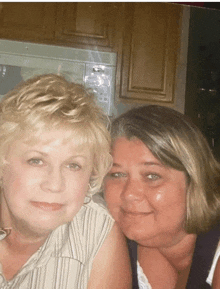 two women posing for a picture in front of a stove