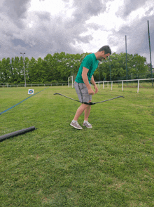 a man in a green shirt is holding a bow in a field