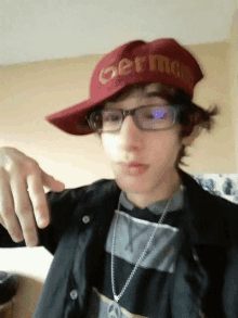 a boy wearing glasses and a red hat that says germany