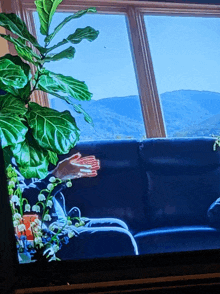 a painting of a person sitting on a couch in front of a window with mountains in the background