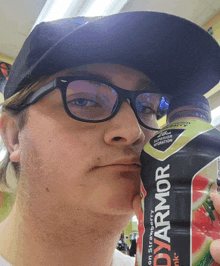 a man wearing glasses and a hat is holding a can of bodyarmor