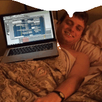 a man laying in bed with a laptop on his lap that says ' adobe ' on the screen