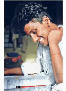 a young man is smiling while reading a book with a pencil