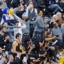 a crowd of people are sitting in a stadium watching a basketball game and a man is standing in the stands .