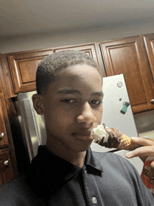 a young boy is eating an ice cream cone in a kitchen