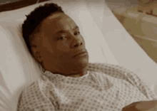 a man is laying in a hospital bed wearing a hospital gown