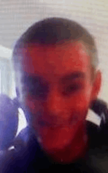 a close up of a man 's face with a blurred background and a red face .