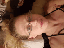 a woman wearing glasses laying on a bed