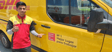 a man in a red and yellow dhl shirt stands in front of a yellow van