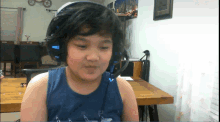 a young boy wearing headphones and a blue tank top with the letter l on it