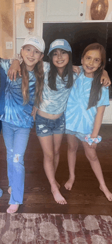 three young girls wearing blue tie dye shirts are posing for a picture together