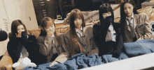 a group of girls in school uniforms are sitting on a couch covering their faces with their hands