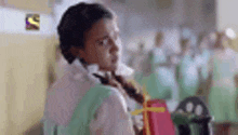 a girl with a backpack is standing in a classroom with other students .