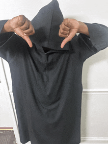 a person wearing a black shirt with a hood giving a thumbs down sign