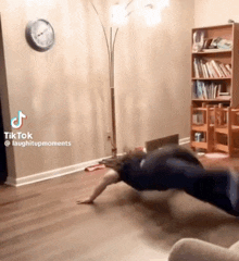 a woman is doing push ups in a living room with a clock on the wall above her