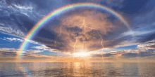 a rainbow and lightning over the ocean during a storm