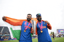 two men holding a trophy and a flag with the word india on their shirts