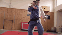 a man and a woman are practicing judo in a gym with a poster on the wall that says karate