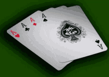 four aces playing cards are stacked on top of each other on a green surface .