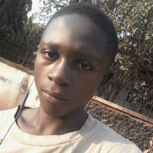 a young man wearing headphones looks at the camera in front of a stone wall