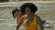 a woman in a yellow swimsuit is in the water with a man