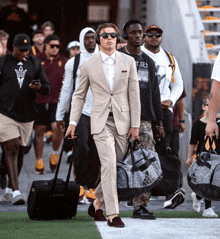 a man in a suit carrying a duffel bag with the word adidas on it