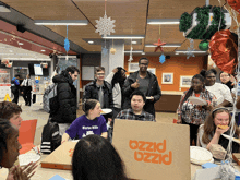 a group of people are gathered around a pizza box