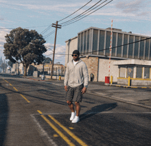 a man in a gray hoodie and shorts walks down a street