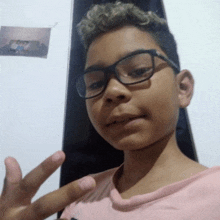 a young boy wearing glasses is giving a peace sign