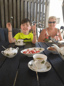 a boy giving a thumbs up while sitting at a table with two women