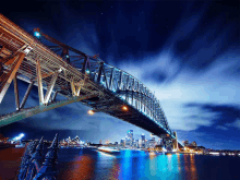 a bridge over a body of water at night with a city in the background