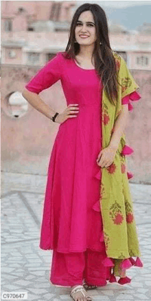 the woman is wearing a pink dress with a green dupatta .