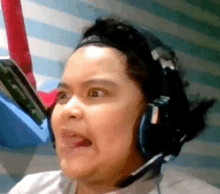 a woman wearing headphones is making a funny face and sticking her tongue out .