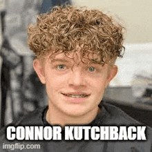 a young man with curly hair and braces is sitting in a chair in a barber shop .