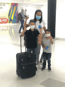 a woman and two children wearing face masks are standing in front of a sign that says 8,413