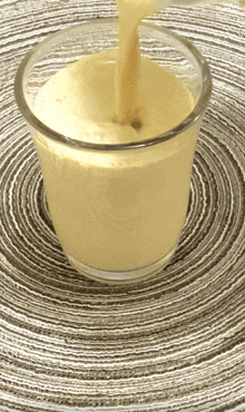 a glass of liquid is being poured into it on a table