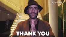 a man in a hat is saying thank you with his hands folded