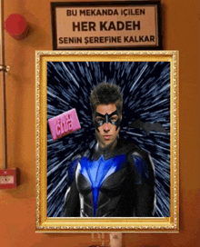 a framed picture of a man in a superhero costume with a sign behind him that says bu mekanda