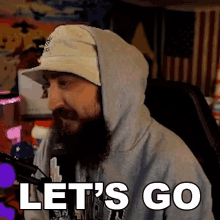 a man with a beard is wearing a hoodie and a hat and says let 's go